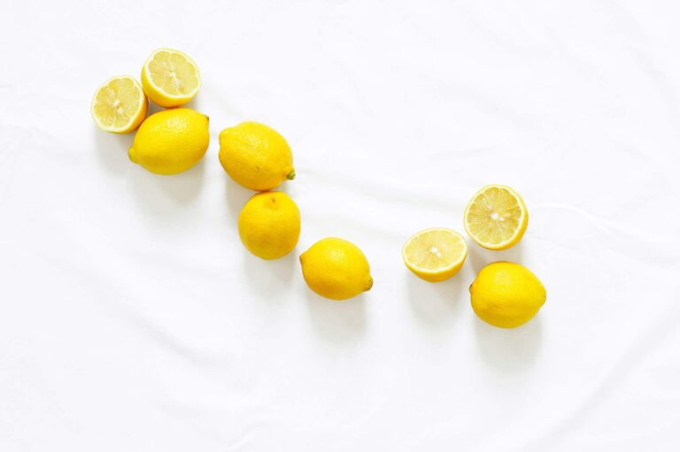 Bright yellow lemons on white fabric. Fresh citrus fruit, some halved. Vitamin C source.
