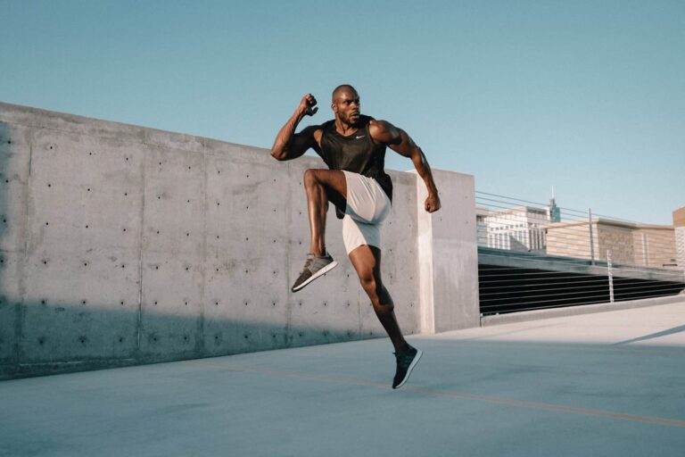 Athletic man doing high knees exercise outdoors. Fitness training, cardio workout. Active lifestyle.