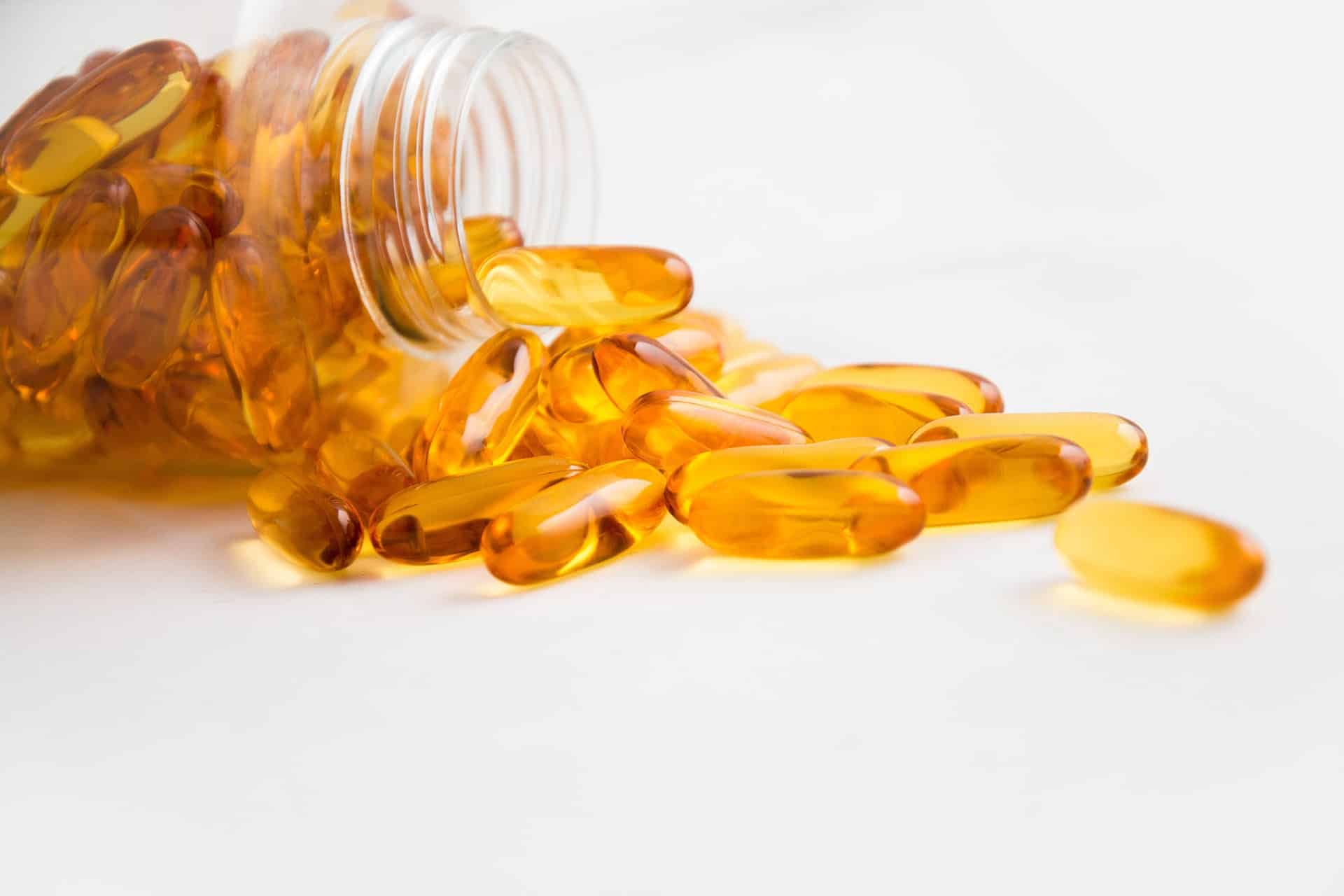 Omega-3 fish oil capsules spilling from a bottle. Dietary supplement with vitamin D for health.