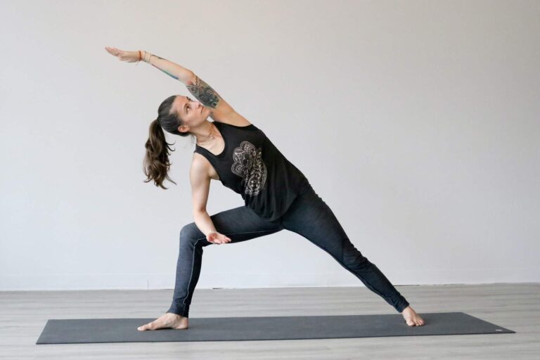 Woman in triangle pose on yoga mat. Yoga instructor demonstrating fitness pose.